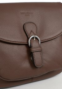 Borsa a tracolla in pelle marrone con finitura testurizzata, dotata di una fibbia e chiusura ad anello in metallo argento. Logo impresso sulla parte anteriore.