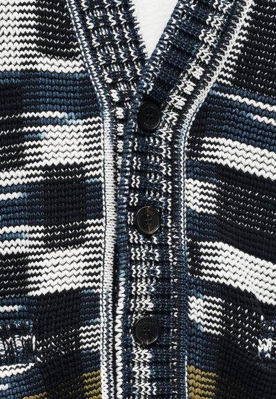 Κοντινό πλάνο μπλε, λευκού και μαύρου πλεκτού ζακετάκι με τρία μαύρα κουμπιά και ριγέ ριμπ περιθώρια.