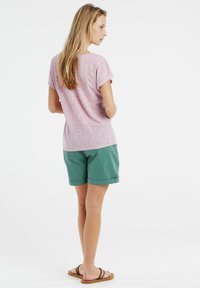 T-shirt à motifs roses avec des manches courtes, associé à un short vert. La tenue présente une coupe décontractée et confortable, ainsi que des textures de tissu douces.