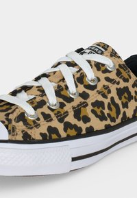 Χαμηλά sneakers με καφέ και μαύρο λεοπάρ μοτίβο καμβά, λευκά κορδόνια και λευκή καουτσούκ σόλα με μαύρη λεπτομέρεια ρίγας.