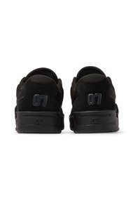 Zwarte sneakers van suede en mesh, met een gevoerde kraag, een gestructureerde zool en het nummer "07" op de hiel.