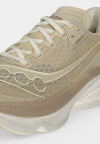 Μπεζ παπούτσι τρεξίματος Saucony Azura με πλέγμα στο πάνω μέρος, υφή στο πλαϊνό λογότυπο, παχιά μαξιλαρωτή σόλα και λευκά κορδόνια δεμένα σε απλό φόντο.