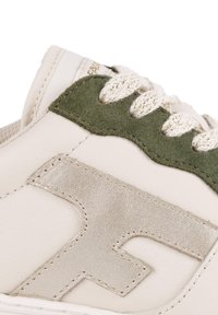 Sneaker in pelle bianca con dettagli in suede verde, logo metallizzato argento, superficie testurizzata e lacci beige. Suola piatta con dettagli di cucitura.