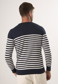 Navy en wit gestreepte trui met lange mouwen, geribbelde manchetten en zoom. Ontworpen voor een aansluitende silhoutte met een ronde hals.