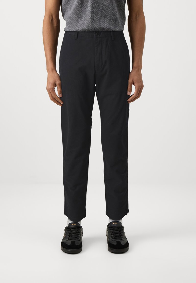 Pantaloni neri a gamba dritta realizzati in tessuto misto cotone, caratterizzati da una superficie liscia e tasche anteriori, abbinati a sneakers nere.