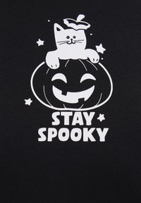 Black fabric featuring a white graphic of a smiling pumpkin with a cat wearing a leaf hat and the text "STAY SPOOKY" underneath.