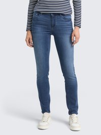 Slim-fit modré džíny s pěti kapsami, jemným vyblednutím a hladkou texturou, zkombinované s bílými teniskami.