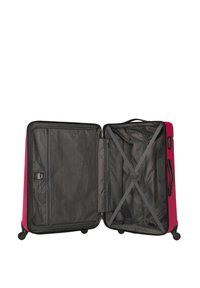 Valise rigide de couleur rose avec des accents noirs. Intérieur en tissu gris, avec des sangles croisées et une poche zippée en mesh. Quatre roulettes pour la mobilité.