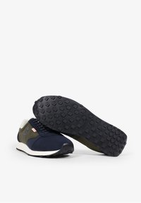Marineblauwe en olijfgroene sportieve schoenen met een bovenwerk van suede en mesh, rubberen zool met een gestructureerd profiel en een contrasterende witte tussenzool.