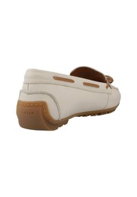 Witte leren mocassin-stijl schoen met bruine accenten, zichtbare stiksels en rubberen zool met textuur voor grip. "GEOX" logo op de hiel.