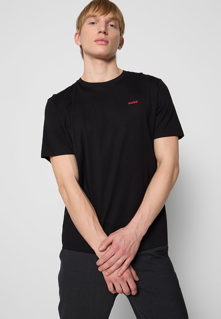 Czarna bawełniana koszulka z okrągłym dekoltem, krótkimi rękawami i małym czerwonym logo "HUGO" na piersi. Gładka tekstura, dopasowany krój.