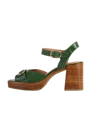 Sandaal de tacón verde de cuero con una correa para el tobillo, que presenta una puntera redondeada y un tacón de bloque de madera con rayas horizontales. Acento de hebilla dorada.