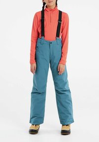 Blå skidbyxor med justerbara svarta hängslen, bärs över en långärmad korallfärgad topp, har sidofickor och en avslappnad passform.