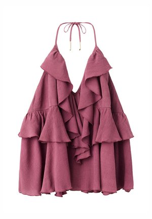 Femme portant un top violet sans manches à volants, un short en jean noir et des sandales marron cloutées, debout sur un fond blanc uni.