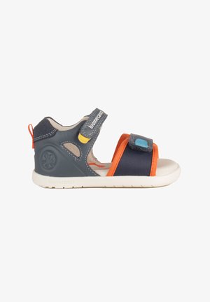 Sandalo per bambini blu navy e arancione con punta aperta, cinturini regolabili e suola bianca, progettato per comfort e supporto.