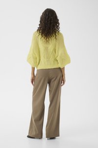 Πλεκτό πουλόβερ σε φωτεινό κίτρινο με άνετη εφαρμογή, υφασμένο μοτίβο στην πλάτη, σε συνδυασμό με καφέ παντελόνια φαρδιάς γραμμής.