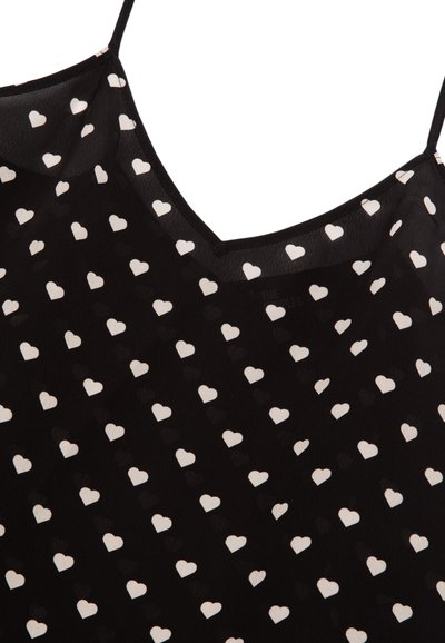 Schwarzes durchsichtiges Camisole mit weißem Herzmuster, ausgestattet mit dünnen Trägern und einem V-Ausschnitt. Glatte Textur, leichtes Gewebe.
