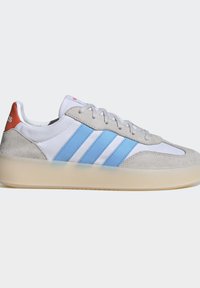 Hvid sneaker med lyseblå striber, grå ruskind detaljer, orange hælkappe, hvide snørebånd og en gennemsigtig beige sål.
