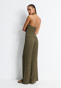 Zeleno-olivový dvoudílný set obsahující form-fitting halter top a široké texturované kalhoty. Tkanina má na povrchu ribbovaný design.