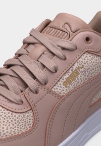 Ροζ ανοιχτό αθλητικό παπούτσι Puma με υφασμένα κορδόνια, πάνελ με σχέδιο λεοπάρδαλης και χρυσό λογότυπο Puma σε λευκή σόλα.