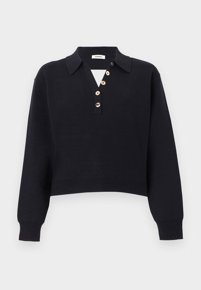 Pull noir en maille à manches longues avec un col et cinq boutons beige disposés en biais le long du plastron de la poitrine, poignets et ourlet côtelés.