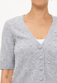 Grijze gebreide cardigan met korte mouwen, voorzien van een diepe V-halslijn, knoopsluiting en versieringen van parels en rhinestones.