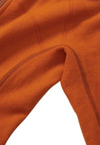 Oranges Fleece-Gewebe mit sichtbaren Nähdetails und einer glatten Textur, das ein enges, geschwungenes Design aufweist.