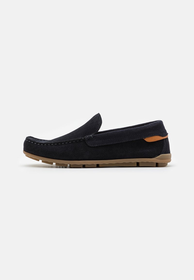 Slip-On-Schuhe aus dunkelblauem Wildleder mit einer sandfarbenen Gummisohle. Sie haben einen leicht erhöhten Absatz und dekorative Nähte entlang der oberen Kante.