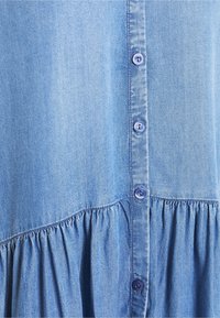 Ljusblå denimklänning med knappslå framtill med sex knappar, insydd midja och mjuk textur.