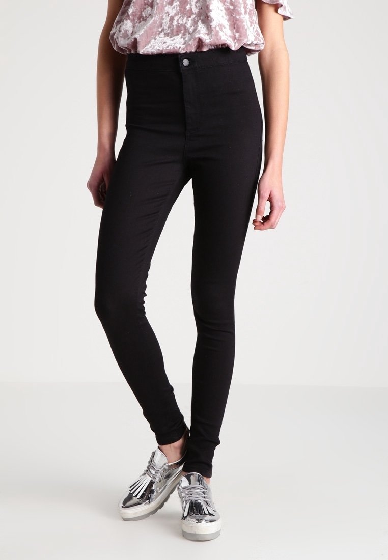 Jeans skinny negros de tiro alto, elaborados con una tela de mezcla de algodón elástica, que presentan una textura suave y un diseño clásico de cinco bolsillos.