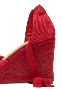 Sandale rouge en cuir tressé à talon compensé, avec lien à nouer autour de la cheville et semelle texturée, mettant en valeur un motif tressé complexe et une construction en tissu.