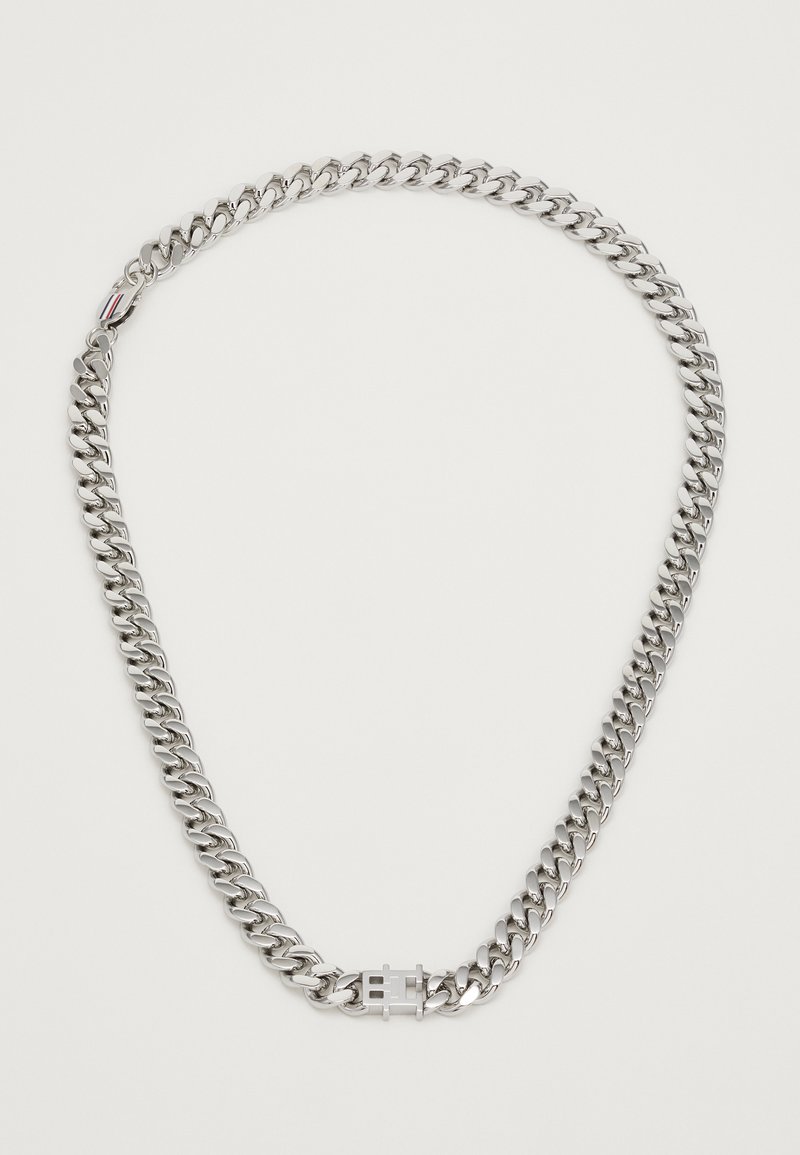 Colar de corrente robusta em prata com um fecho retangular que apresenta um design gravado e um pequeno detalhe riscado perto do fecho.