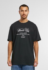 Black cotton t-shirt with short sleeves, featuring white text printed on the front: “Winners Club” and additional Parisian details below.