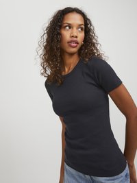 Svart ribbestrikket t-skjorte med korte ermer, tettsittende design, glatt tekstur og rund hals. Brukt sammen med lys blå denimshorts.