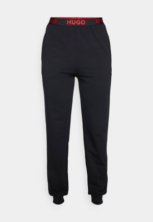 Black sweatpants with a fitted ankle cuff, featuring a red elastic waistband with "HUGO" logo. Made of soft fabric for comfort.