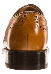 Scarpa brogue in pelle marrone con perforazioni decorative, punta arrotondata e tacco nero. Sono visibili i dettagli delle cuciture sul tacco e sulla parte superiore.