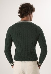Tmavě zelený pletený svetr s texturovaným kabelovým vzorem, slim fit a kontrastním bílým pruhovaným límcem a manžetami.