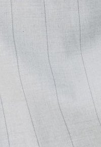 Světlá šedá lněná tkanina s jemnými svislými pruhy a měkkým, texturovaným povrchem. Prošívané detaily zdůrazňují strukturu a design.