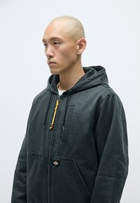 Σκοτεινή κουκούλα ζακέτα από υφασμάτινη υφή, με φερμουάρ και ξύλινη πεταλούδα, καθώς και λάβαρο λογοτύπου μπροστά.