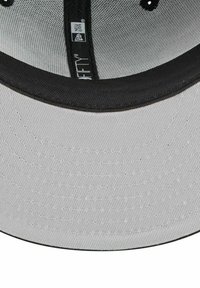 Graue Mütze mit schwarzem Schirm und Naht. Innen mit einem schwarzen Stoffband und Markenkennzeichnung. Oberfläche mit strukturierter Optik.