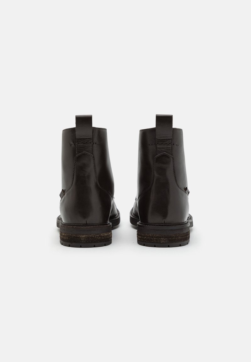 Mustad mustad nahast pahkluu saapad sujuva viimistlusega, madala kontsaga ja tagumiste tõmbenööpidega, mis on mõeldud lihtsaks selga panemiseks.