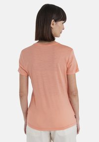 T-shirt a maniche corte, con scollo rotondo, di colore pesco chiaro, realizzato in tessuto leggero con una texture liscia e un sottile motivo melangiato.