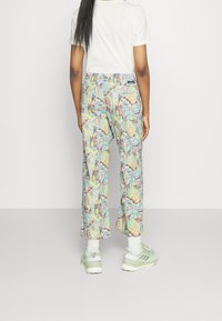 Colorful patterned wide-leg pants with abstract designs in blue, green, and orange. Paired with light green sneakers and white ankle socks.
