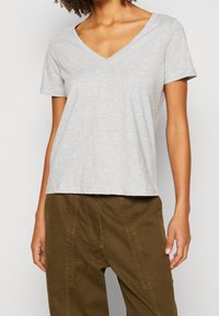 Grijs T-shirt met korte mouwen en V-hals, gemaakt van lichtgewicht stof, met een ontspannen pasvorm en een gladde textuur, gecombineerd met olijfgroene broek.