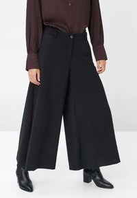 Pantalons noirs à jambes larges en tissu lisse avec une taille ajustée, dotés d'une fermeture à bouton sur le devant et de poches latérales.