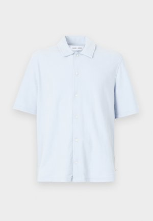 Valkoinen lyhythihainen paita, joka on valmistettu pehmeästä kankaasta. Paitassa on nappisuljenta ja klassinen kaulustyyli.