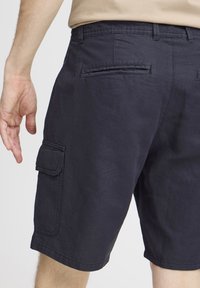 Marineblå cargo shorts laget av bomullstwill, med en sidelomme, beltehemper og baklommer med flat design.