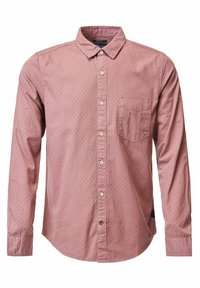Maglietta a maniche lunghe rosa con colletto a bottoni, caratterizzata da un piccolo motivo a pois e una tasca sul petto a sinistra.