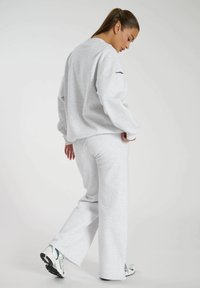 Szary sweatshirt i pasujące dresy wykonane z miękkiego materiału. Cechuje je luźny krój, okrągły dekolt oraz boczne szczeliny w spodniach.