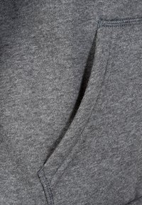 Tessuto grigio del felpa con una texture morbida e una tasca frontale. Cuciture visibili lungo i bordi, che offrono un design informale.